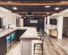 a kitchen with an island and bar stools next to it, in the middle of a room