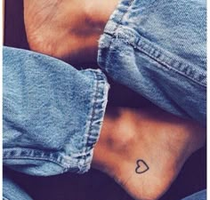 two people with tattoos on their feet sitting next to each other and one has a heart tattooed on the foot