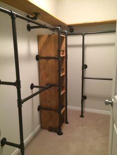 an open closet with metal pipes and wooden shelves