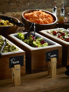 there are many different types of salads in the trays on the table together