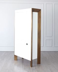 a tall white cabinet sitting on top of a hard wood floor next to a wall