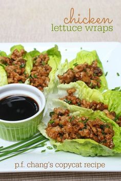 lettuce wraps filled with meat and sauce on a white plate next to a cup of dipping sauce