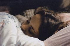 a woman laying in bed with her eyes closed