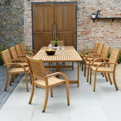 an outdoor dining table and chairs set up in front of a brick wall with wooden doors