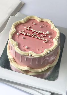 a pink birthday cake sitting on top of a table