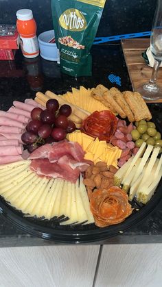 an assortment of cheeses, meats and grapes arranged in a circle on a platter