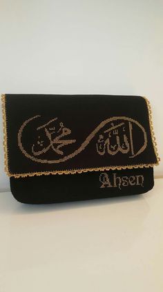 an embroidered clutch bag with arabic writing on the front and side, in gold thread