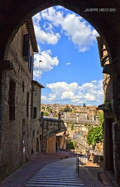 an arch leading into the city with buildings on either side and blue sky in the background