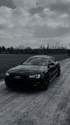 a black and white photo of a car on a dirt road