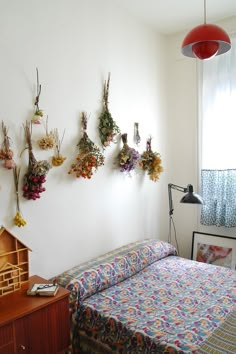 a bed room with a neatly made bed and flowers hanging on the wall above it