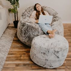 a woman sitting on a bean bag chair using a laptop