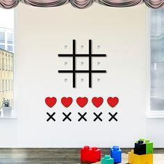 a room with a cross and hearts on the wall next to colorful blocks in front of a window