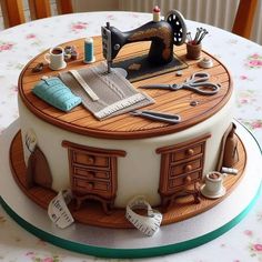 a cake that is sitting on top of a table with sewing tools and thread spools