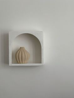 a white vase sitting on top of a shelf