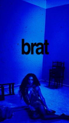 a woman sitting on the floor in front of a blue wall with the word bratt