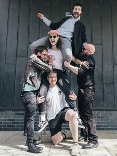 a group of people standing around each other on top of one another in front of a building