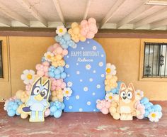 an outdoor birthday party with balloons and decorations on the ground, including a cat balloon arch that says happy birthday