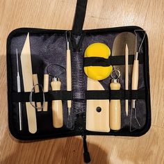 an assortment of kitchen utensils in a black case on top of a wooden table