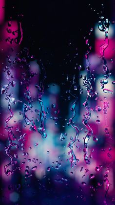 rain drops on the window with pink and blue lights in the backgroung