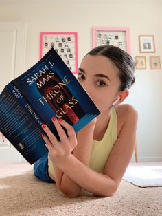 a woman laying on the floor reading a book with her hands in front of her face