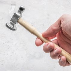 a hand holding a hammer with a wooden handle