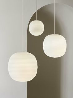 three white lamps hanging from the ceiling in a room with grey walls and flooring