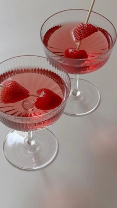 two glasses filled with red liquid and strawberries