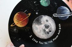 a hand holding up a record with pictures of planets on it and the words i love you to the moon and back