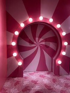 a pink and white room with lights on the wall, an oval mirror in the shape of a lollipopo