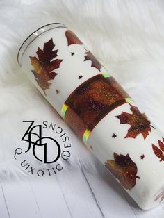 a white and gold tumbler with autumn leaves on it