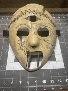 a mask with holes in it sitting on top of a table next to a ruler