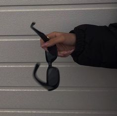 a woman holding onto the side of a pair of black sunglasses in front of a garage door