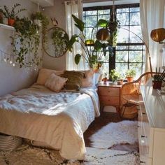 a bed room with a neatly made bed and lots of plants on the windowsill