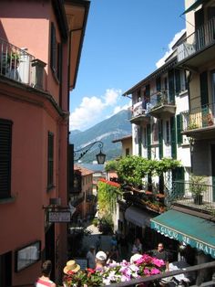 people are walking down the street in front of some buildings with balconies on them