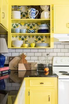 a kitchen with yellow cabinets and black counter tops, white tile backsplashes