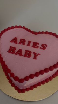 a pink heart shaped cake with the words aries baby on it's side