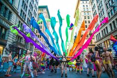 a group of people walking down a street holding kites