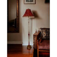 a lamp sitting on top of a wooden table next to a chair and mirror in a room