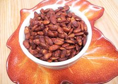 a white bowl filled with nuts sitting on top of a wooden table next to an orange flower