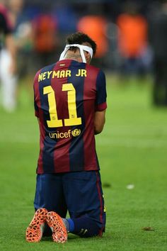 a man sitting on the ground with his head in his hands, wearing a soccer uniform