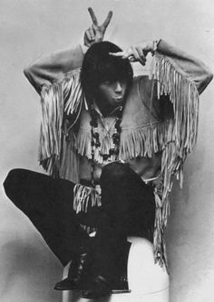 an old black and white photo of a man sitting on a toilet with his hands in the air