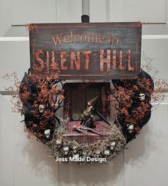 a welcome to silent hill sign hanging from the side of a door with dead plants