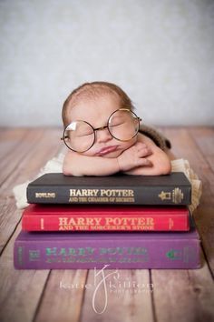 a baby wearing glasses laying on top of three harry potter books, with his head resting on the stack