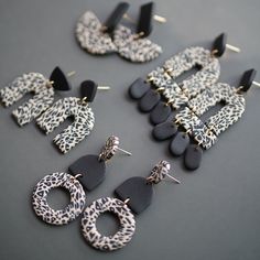 several pairs of animal print and black acrylic earrings on a table with pins