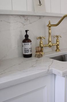 a kitchen sink with a gold faucet and soap dispenser next to it