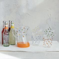 four different colored bottles and glasses sitting on a table