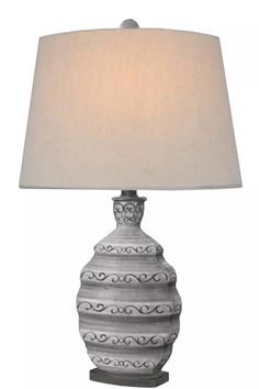 a table lamp with a white shade on it's base and an ornate design