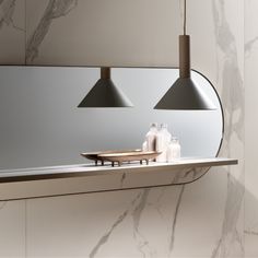 a bathroom mirror with two lights hanging over it's edge and soap bottles on the counter