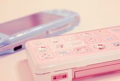 a pink nintendo wii game controller sitting next to a silver cell phone on a table