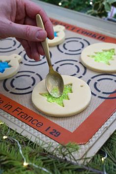 someone is spooning green icing onto decorated cookies